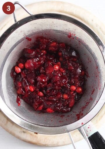 straining cooked cherries through a sieve into a saucepan.