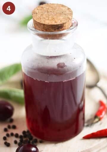 a bottle with cherry vinegar inside with a large cork on top.
