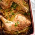chicken and scalloped potatoes sprinkled with parsley in a dish.