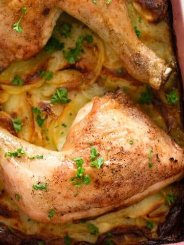 chicken and scalloped potatoes sprinkled with parsley in a dish.