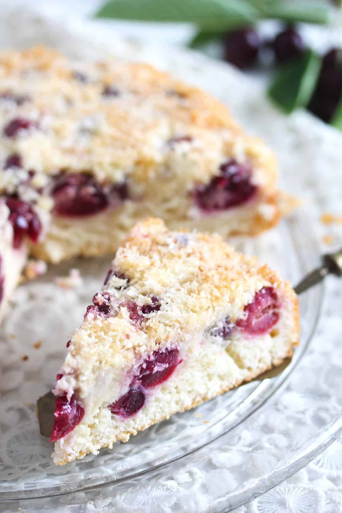 a slice of cherry coconut cake on a cake lifter.
