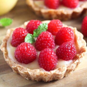 one lemon raspberry tart topped with fresh raspberries and mint leaves.
