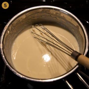 adding milk to roux in a pot to make bechamel sauce.
