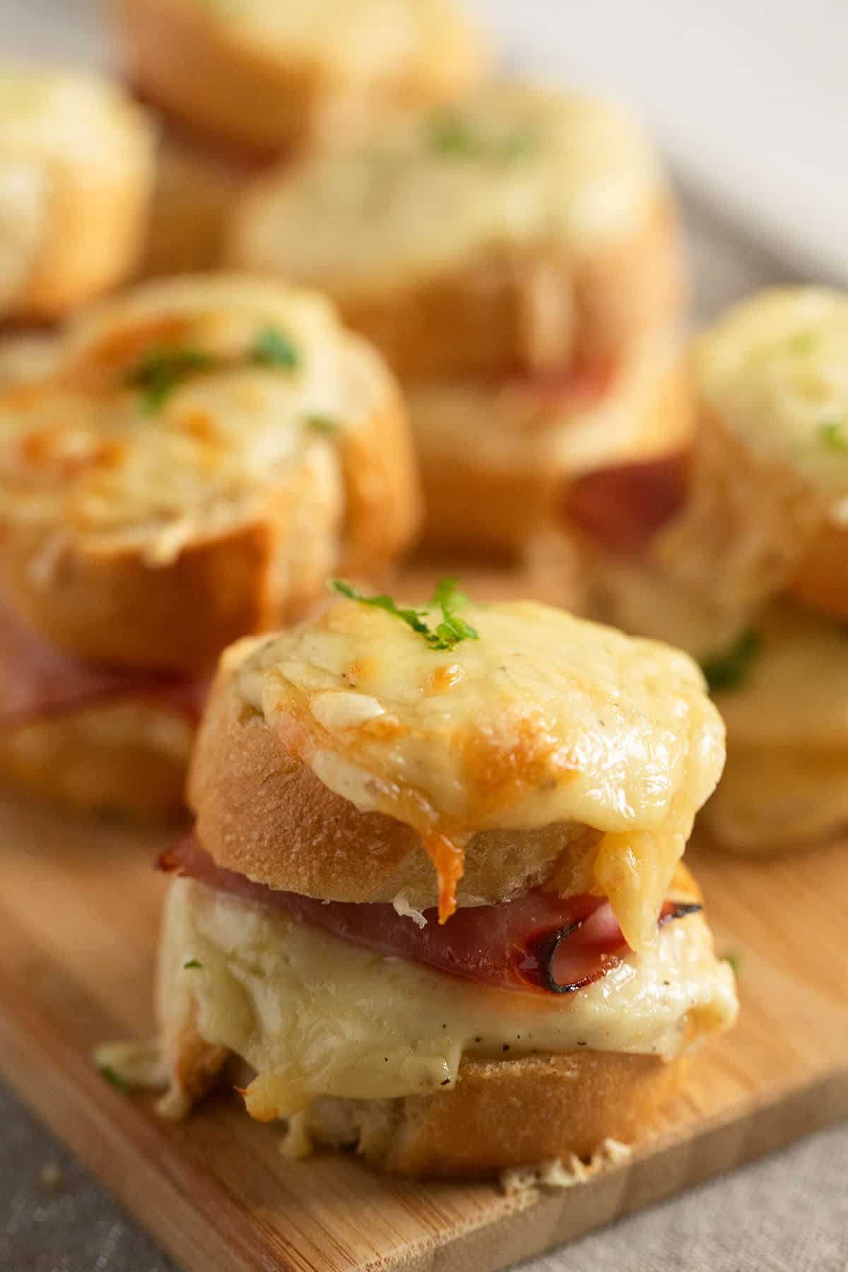 several mini croque monsieur sandwiches on a board.