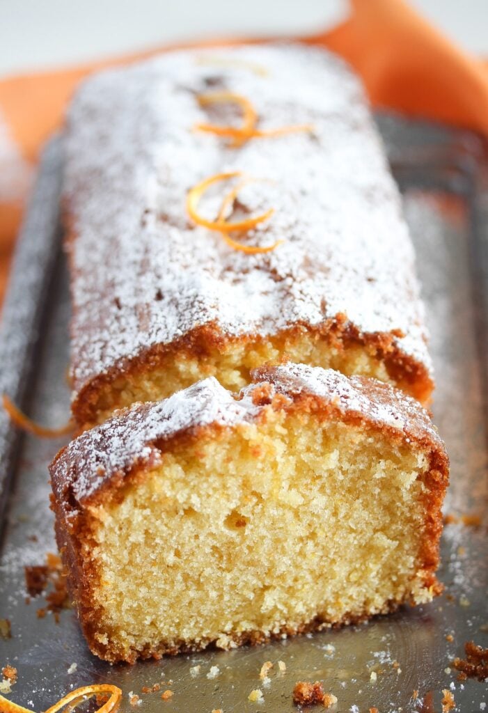 sliced loaf of orange drizzle cake on a silver platter