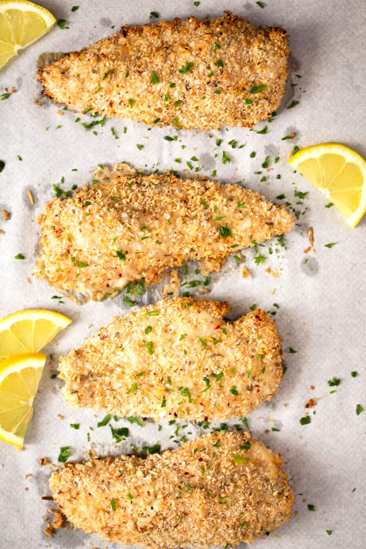 four pieces of panko crusted chicken without eggs with lemon slices.
