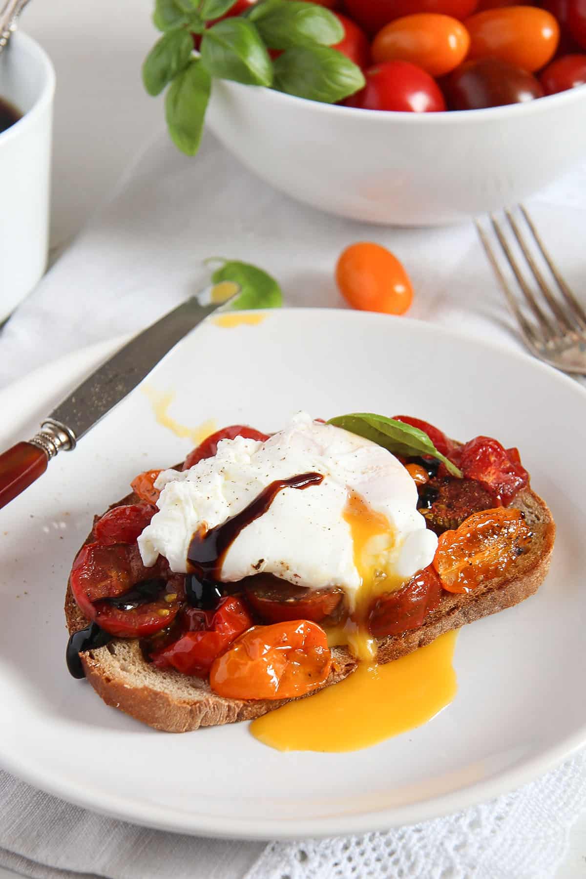 a sourdough toast with roasted tomatoes and a poached egg on top.