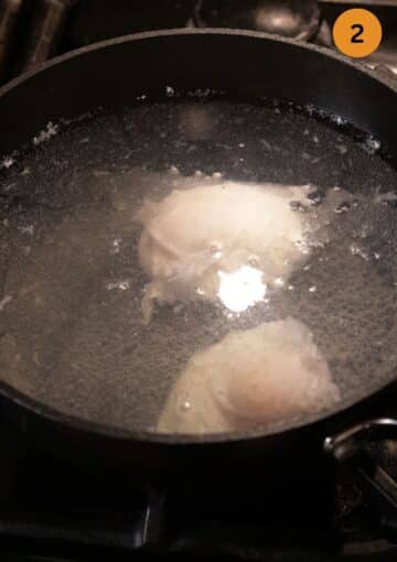 two eggs poaching in a pan.