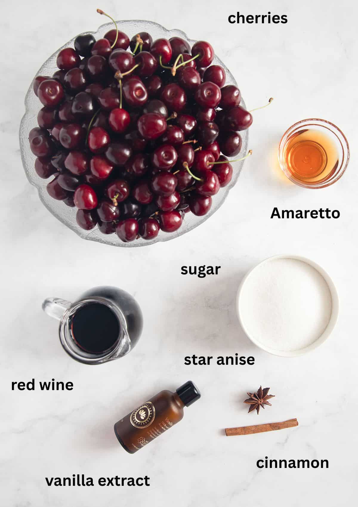 labeled ingredients for making cherries with red wine, amaretto, vanilla, sugar, cinnamon, and star anise.