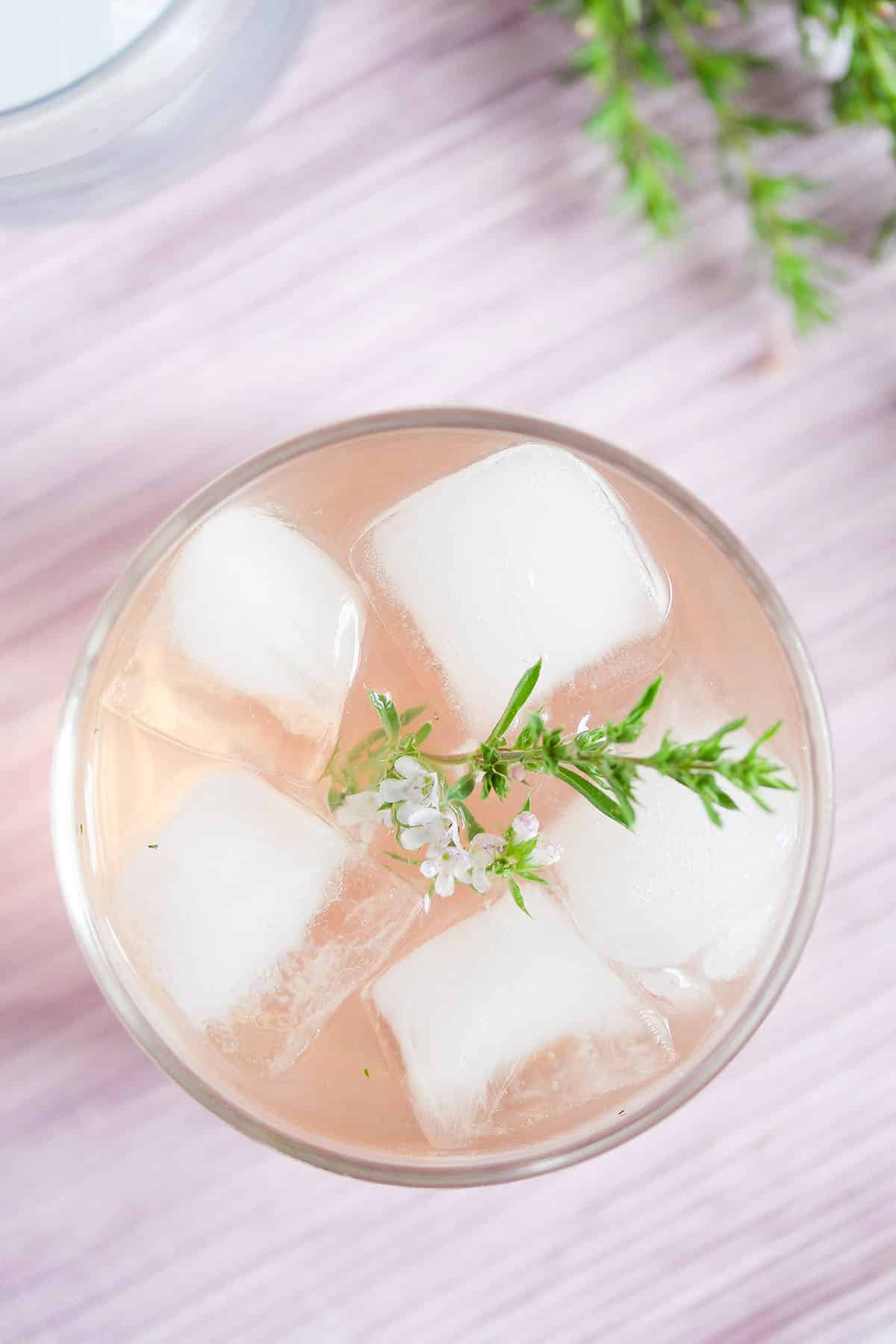 overhead view of a glass of rhubarb gin with ice cubes.