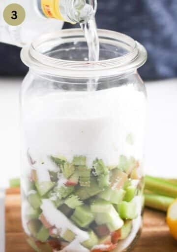 pouring gin over chopped rhubarb and sugar in a tall jar.
