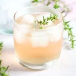 ginger and rhubarb gin in a small glass with thyme on top.