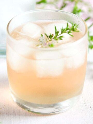 ginger and rhubarb gin in a small glass with thyme on top.