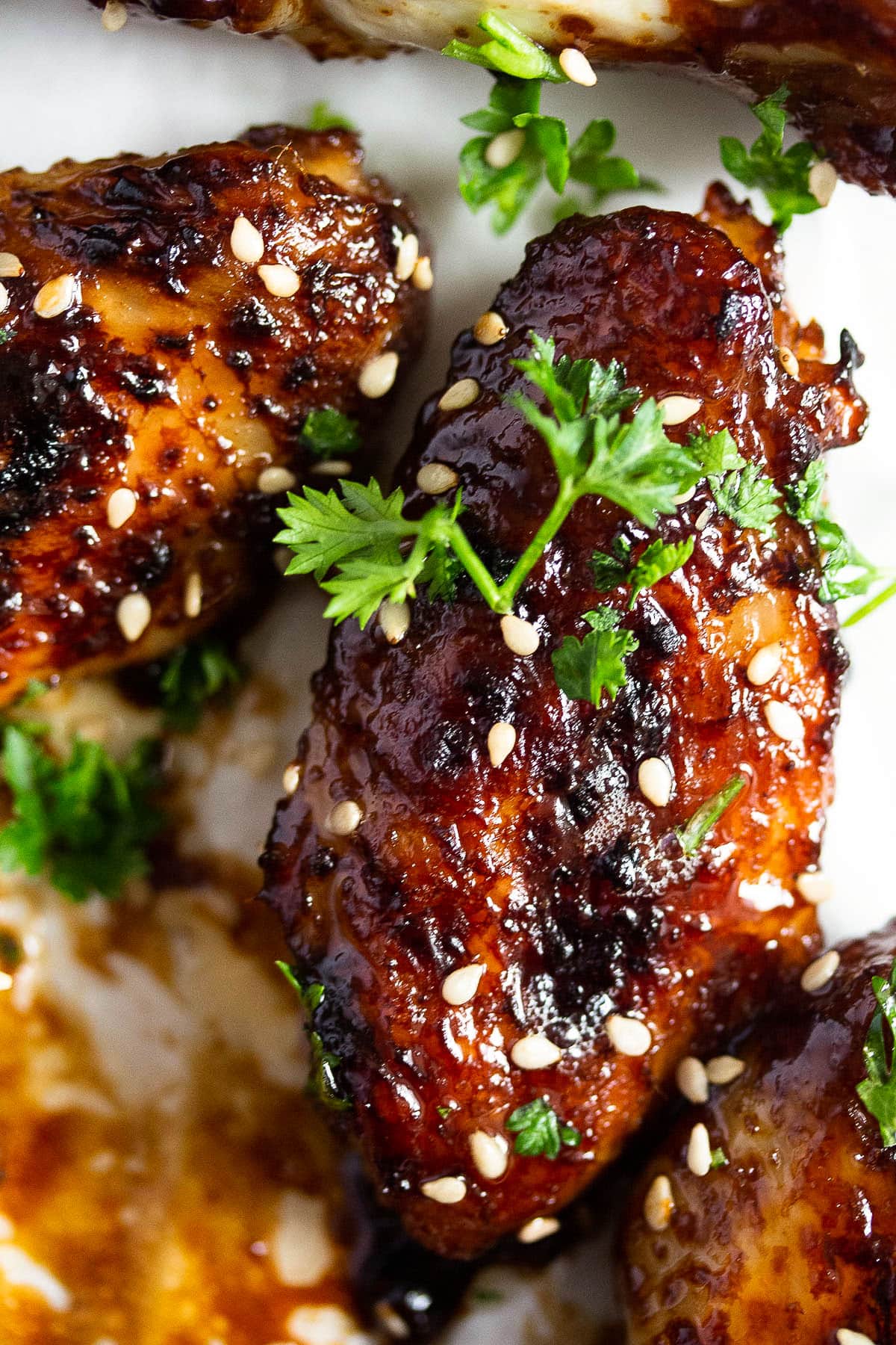 close up of one sticky wing coated with sauce and sprinkled with parsley.