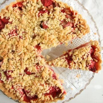 sliced strawberry rhubarb tart with crumble topping close up.