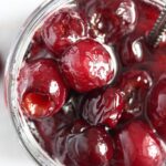 glossy cherries in syrup seen from above in a jar.