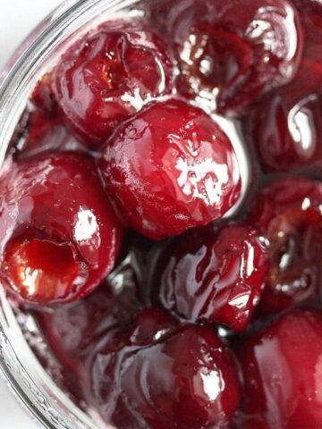 glossy cherries in syrup seen from above in a jar