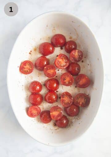 small tomatoes seasoned and ready for roasting in an oval baking dish.