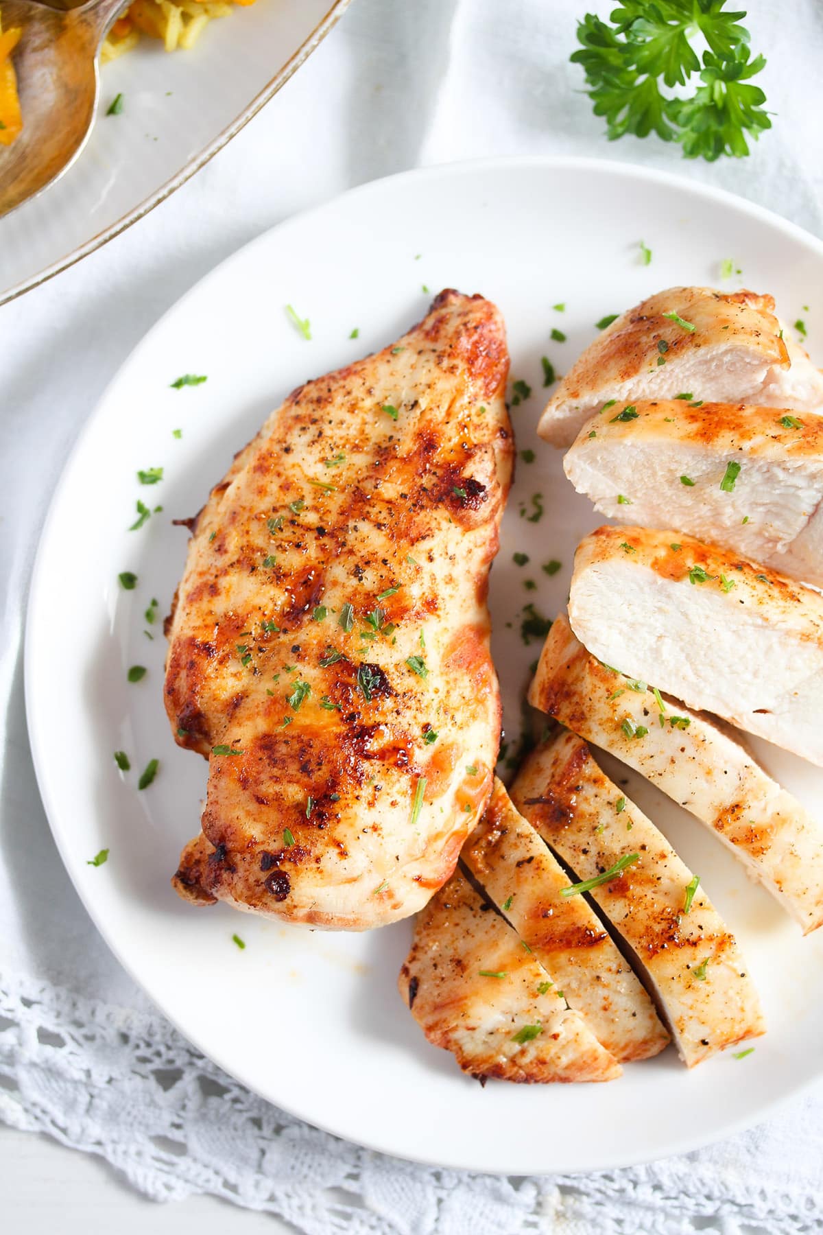 two pieces of air fried frozen chicken breast, one of them sliced.