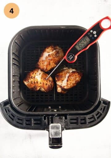 instant read thermometer sticking in chicken breast in an air fryer basket showing the internal temperature.