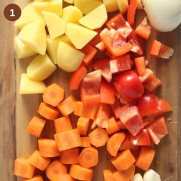 chopped carrots, onions, peppers and potatoes on a wooden cutting board.