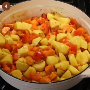 raw chopped potatoes and vegetables in a cooking pot on the stove top.
