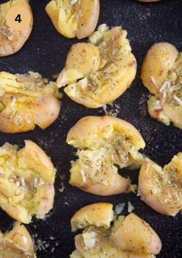 smashed potatoes with garlic on a tray before baking.