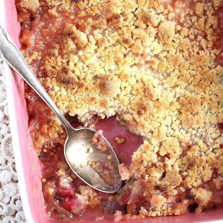 serving gooseberry crumble with a silver spoon from a bakind dish