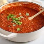 italian meat sauce sprinkled with small basil leaves in a dutch oven.