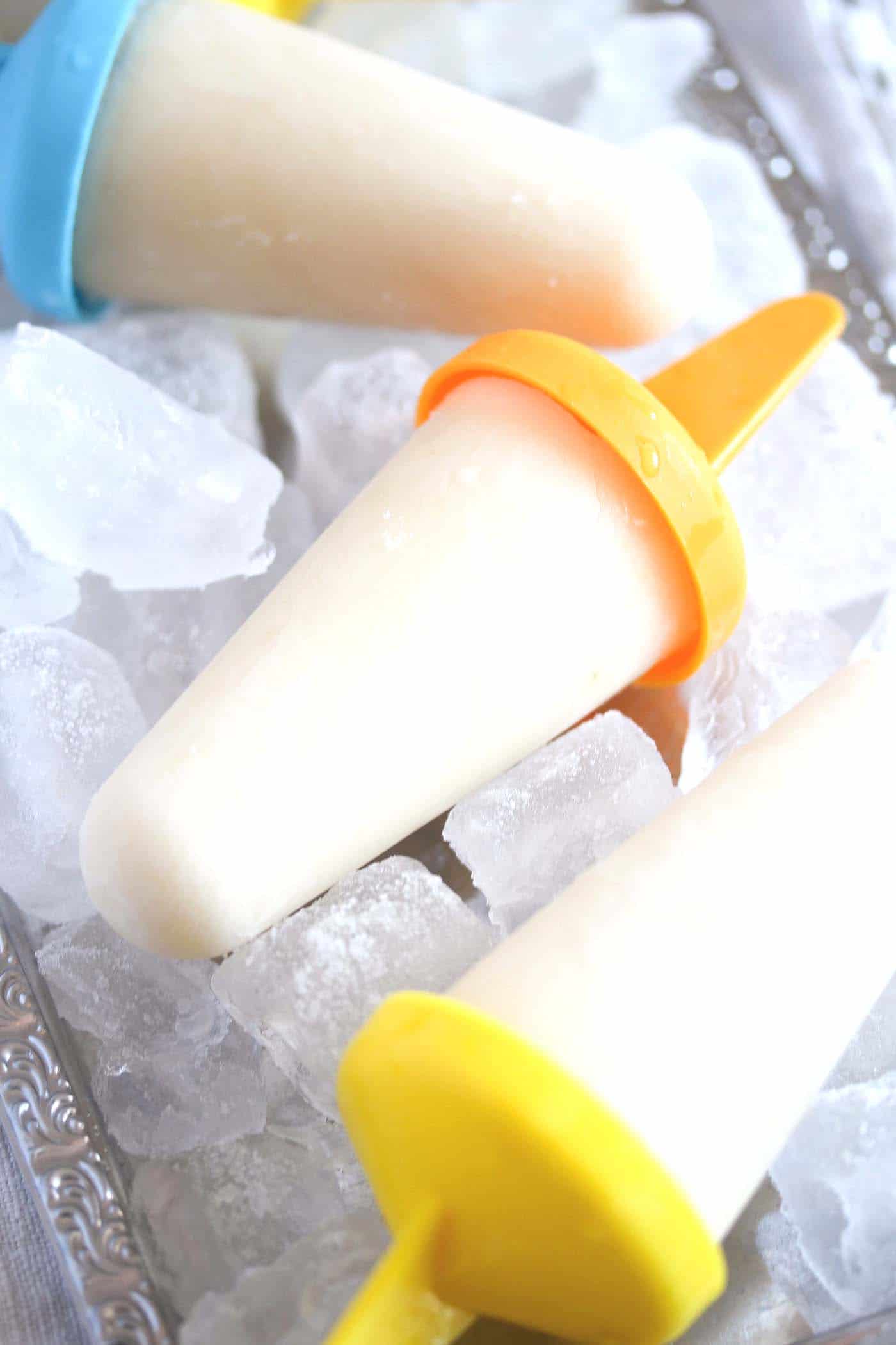 lime popsicles with orange stick on a ice