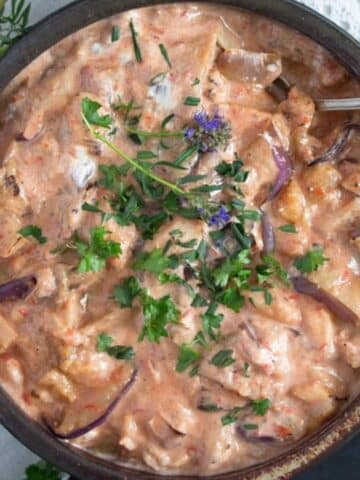 persian eggplant dip sprinkled with parsley and purple edible flowers.