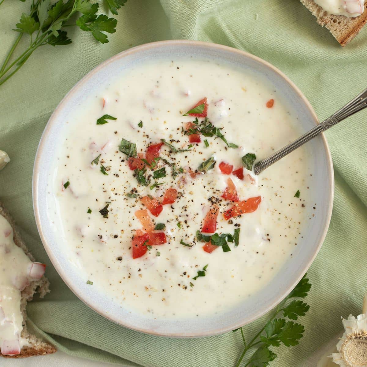 the best garlic sour cream sauce in a bowl with a spoon in it.