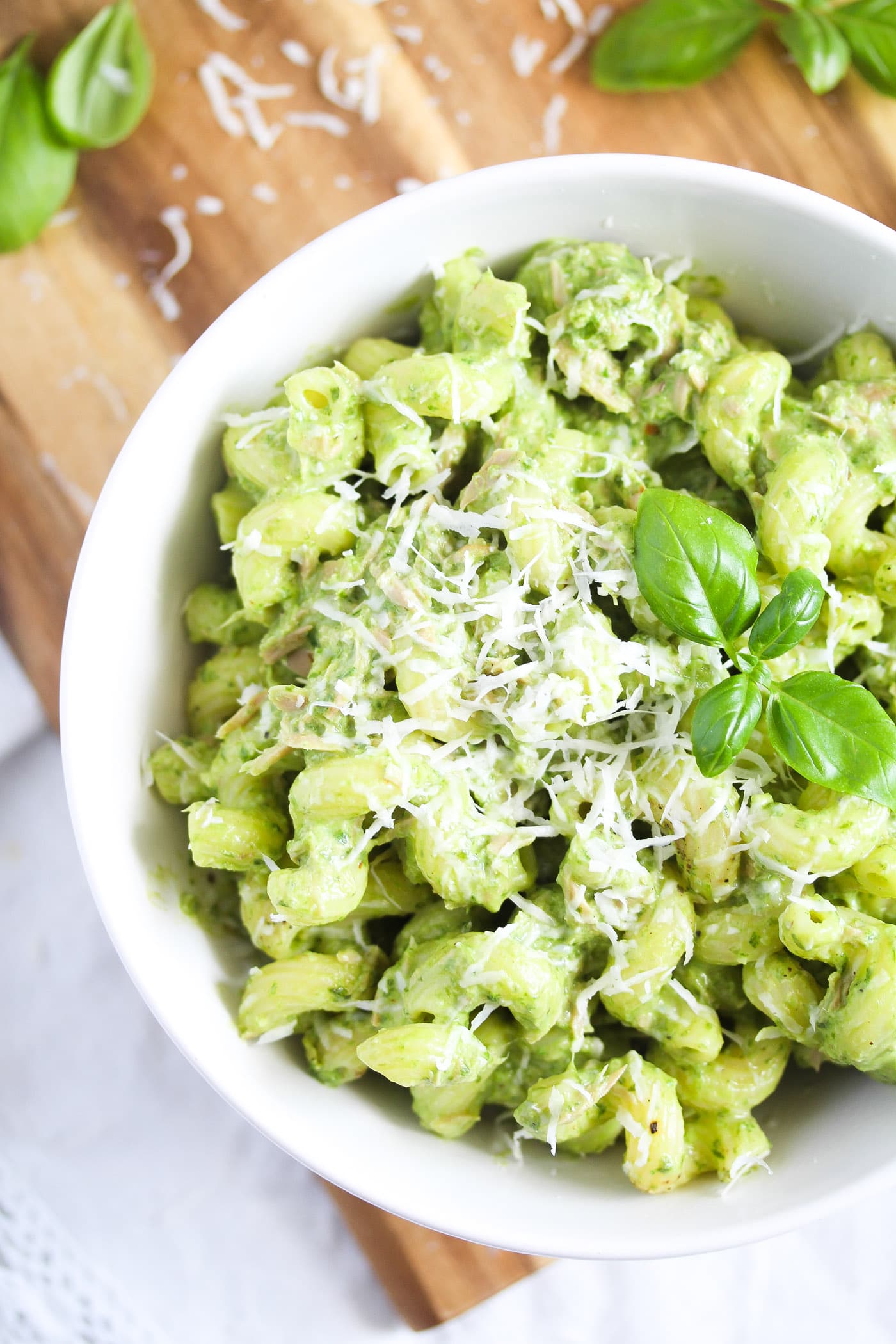 close up green tuna pasta sprinkled with parmesan and topped with basil leaves