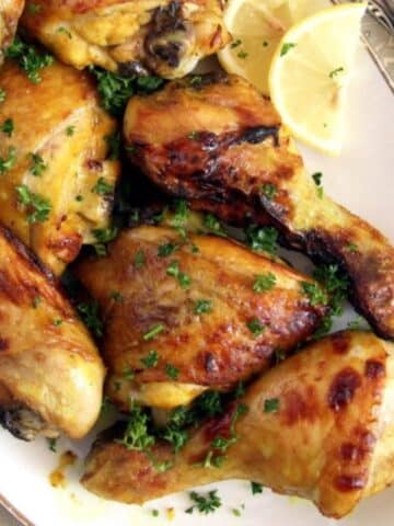 turmeric chicken sprinkled with parsley and lemon wedges on the side of the plate.