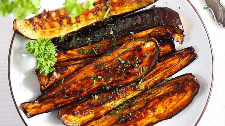 air fryer aubergines with honey glaze on a white plate with parsley.