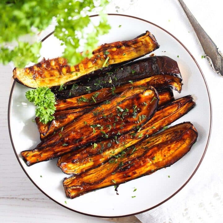 air fryer eggplants with honey glaze on a white plate with parsley