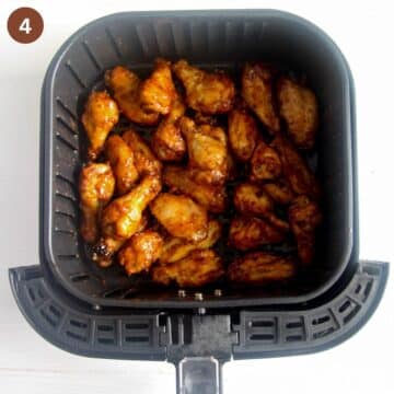 wings coated in sauce in the air fryer basket.