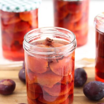 jars of preserved plums on a wooden board