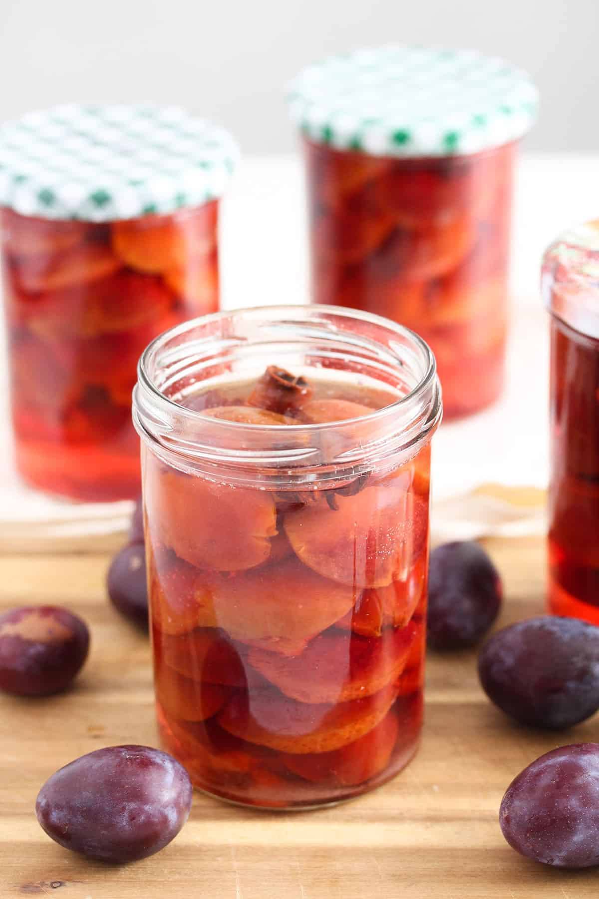 jars full of canned plums, and small plums around the jars.