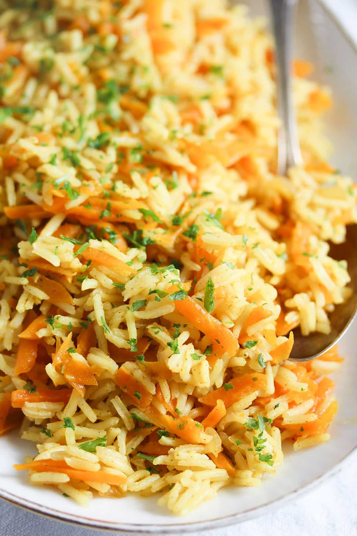 fluffy rice with carrots sprinkled with parsley on a platter.