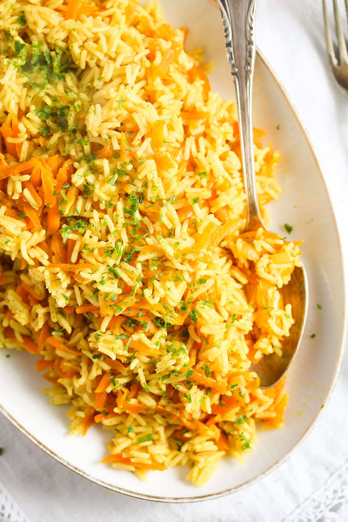 platter full of curried carrot rice and a spoon.