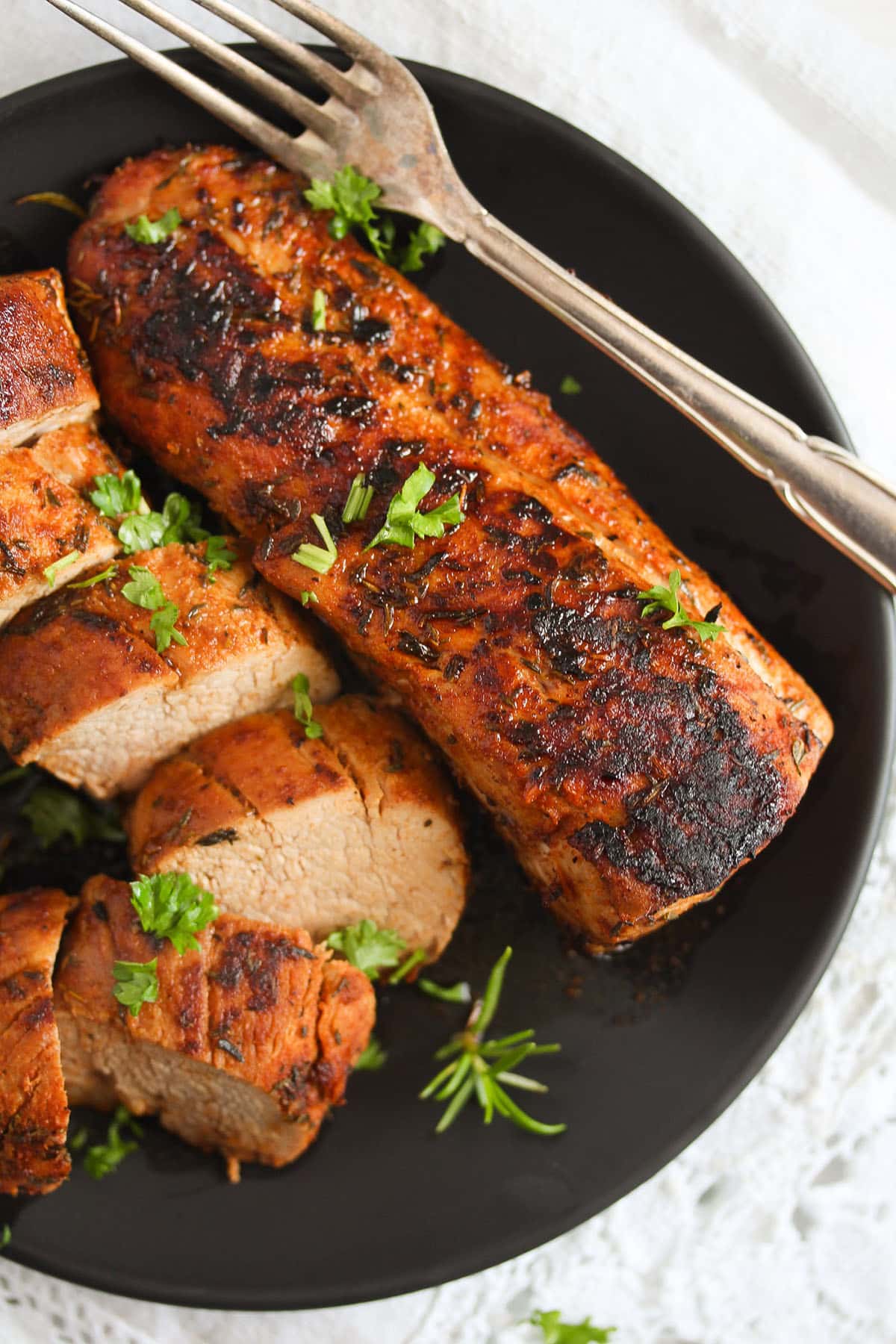 plate with two pork tenderloin, one of them is thickly sliced.