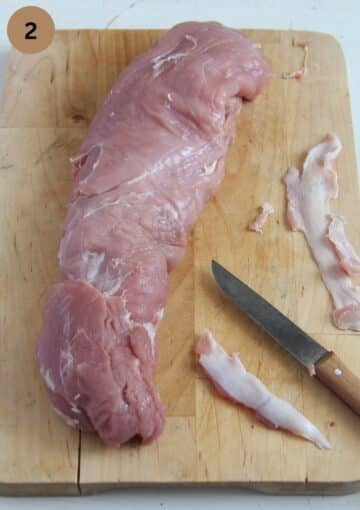 removing the silver skin from a pork fillet with a small knife.