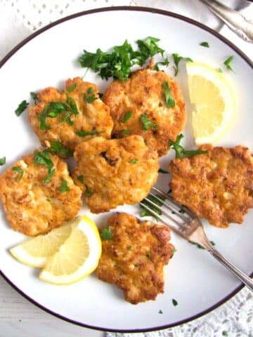 chicken breast patties on a plate with lemon slices.