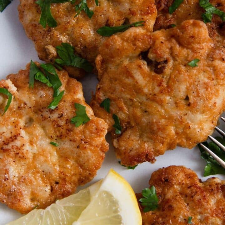 chicken breast patties on a plate with lemon slices.