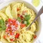 avocaod pasta in a dish sprinkled with tomatoes and herbs