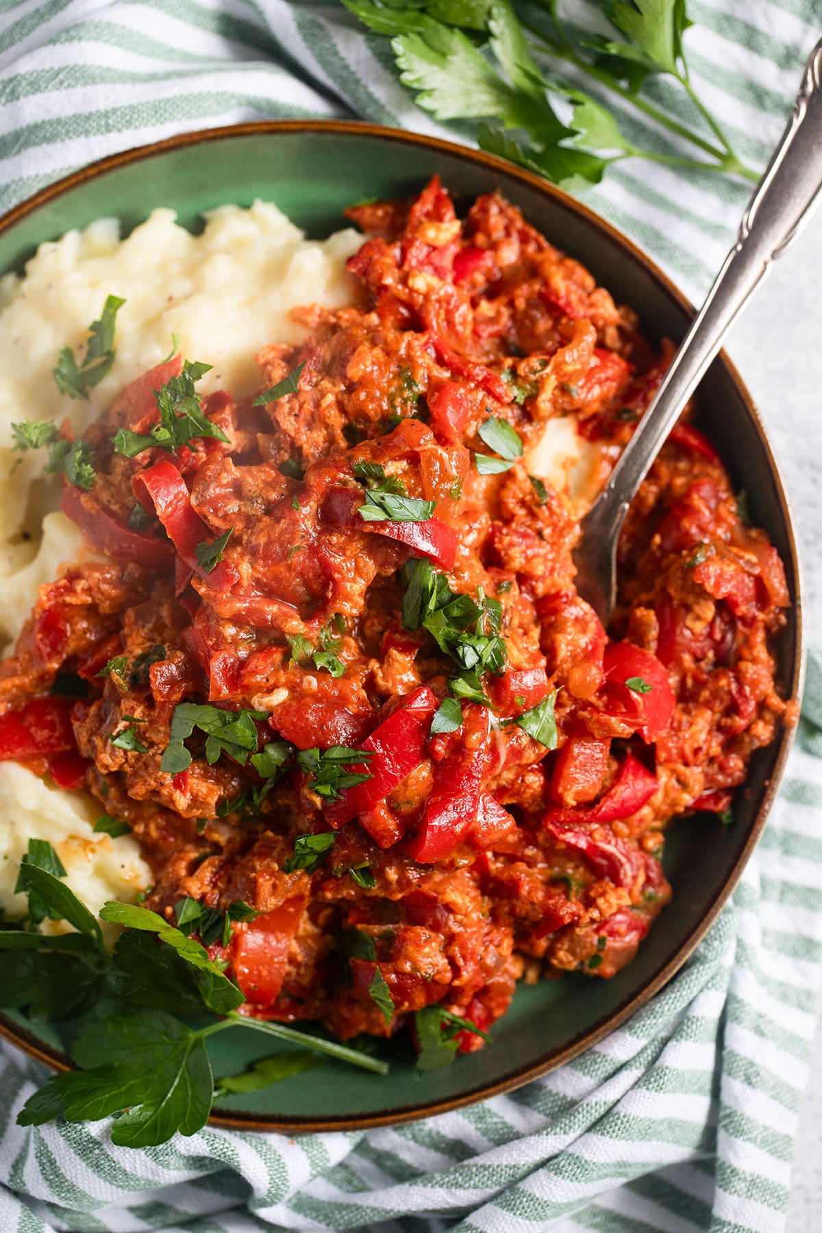 Hungarian lecso recipe served with mashed potatoes, with a spoon in the bowl.