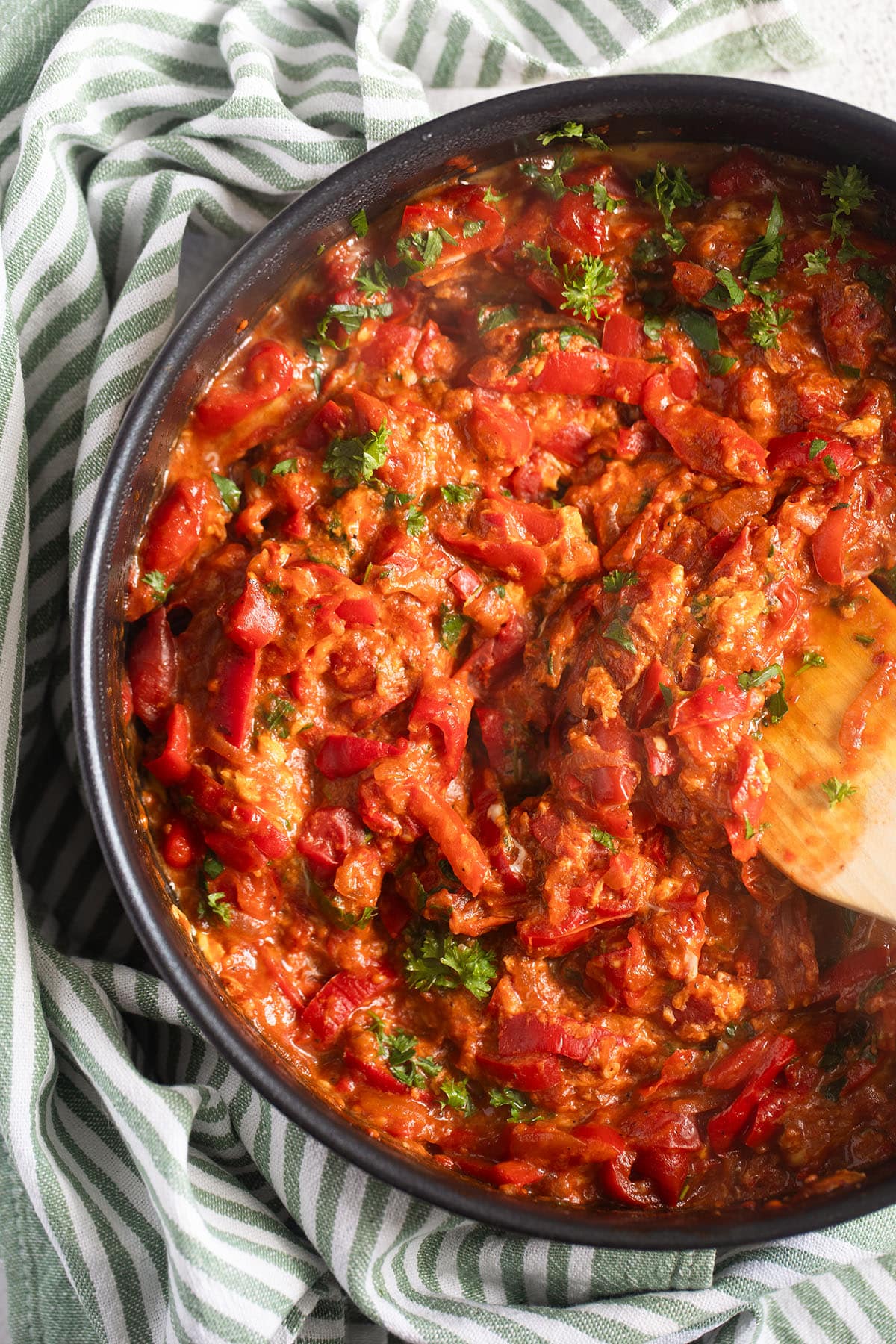 traditional Hungarian pepper and tomato stew stirred with a wooden pan in a skillet.
