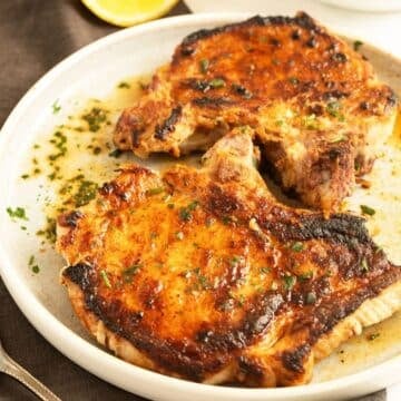 two juicy and golden milk-brined pork chops on a plate.