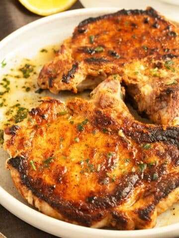 two juicy and golden milk-brined pork chops on a plate.